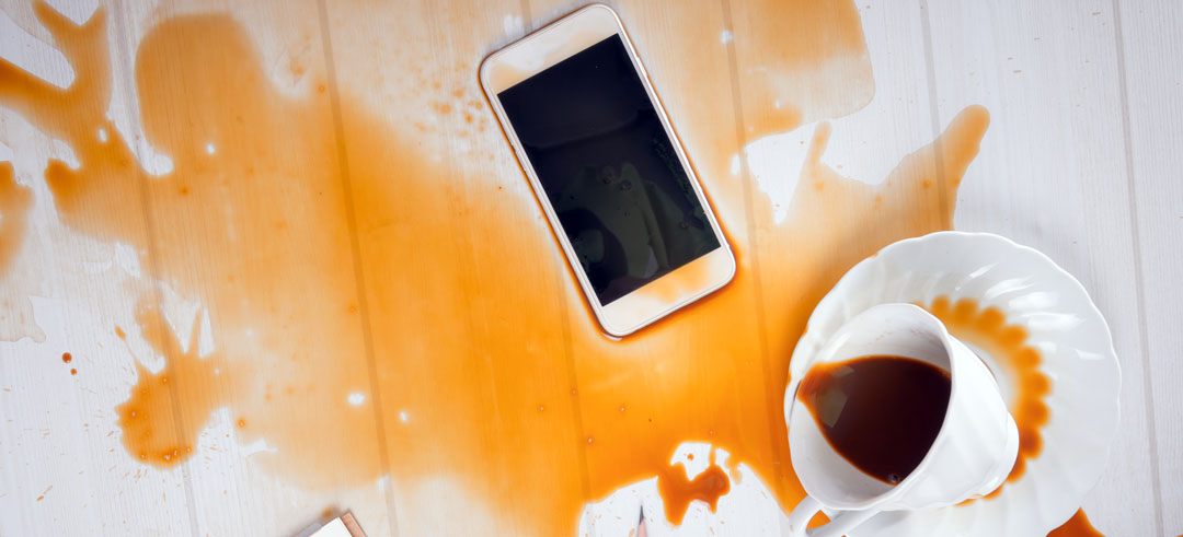 Teléfono manchado de café al caerse una taza cerca