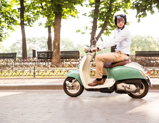 Chico joven conduciendo una moto scooter