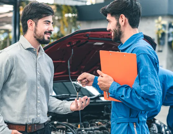 Mecánico dando las llaves de un coche a un hombre en un taller