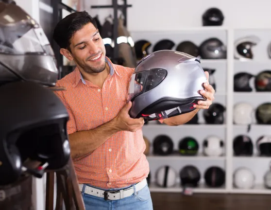 Hombre observando un casco de moto sujetado por sus manos