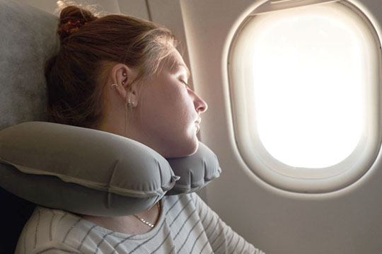 Chica joven durmiendo cerca de la ventana de un avión 